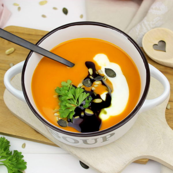 Kürbissuppe mit Hokkaido, Möhren und Kokosmilch serviert mit Petersilie, Kürbiskernen und Kürbisöl